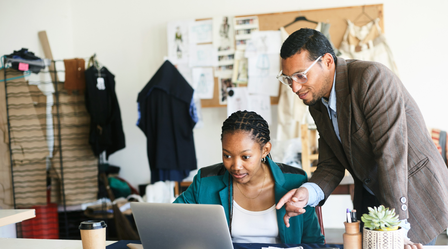Teamwork in a Fashion Design Studio: A Mentor Guides a Designer on a Laptop Teamwork in a Fashion Design Studio: A Mentor Guides a Designer on a Laptop