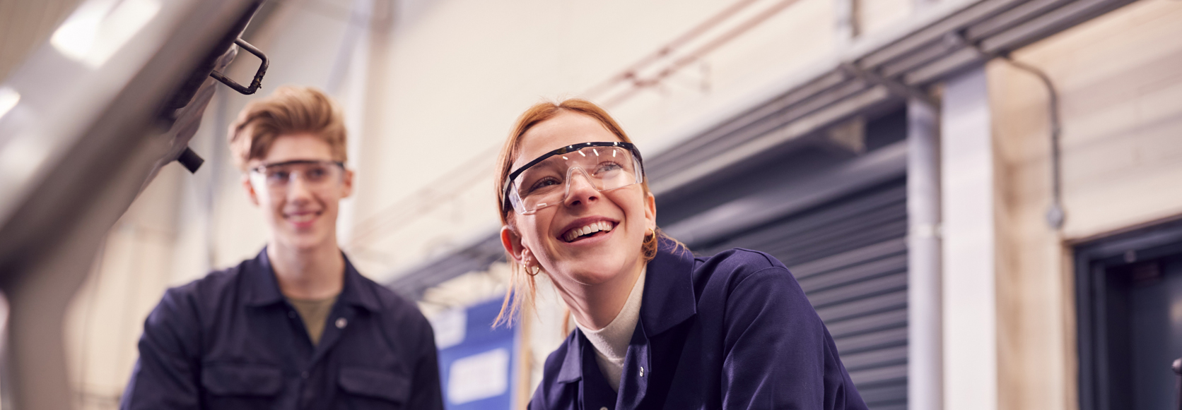 Diverse group of professionals, including a Black woman, a woman with curly hair and glasses, and a white man with gray hair, engaged in a cheerful discussion at a desk.