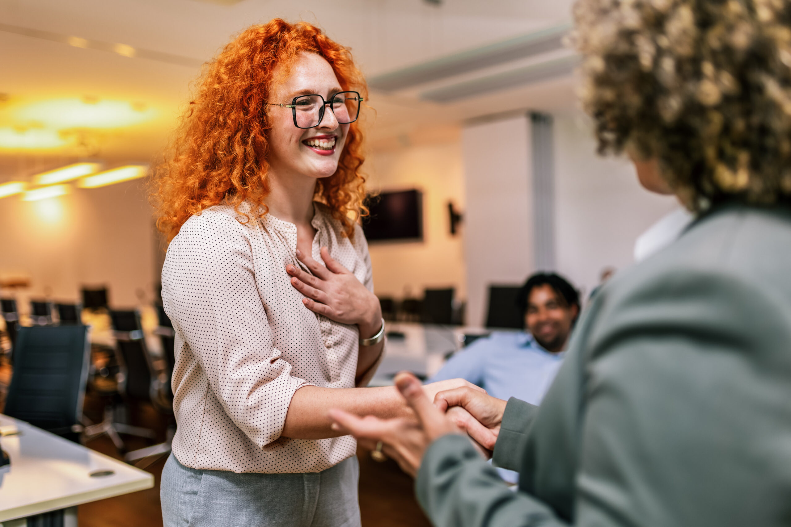 African American woman from Human Resources congratulates the new ginger employee of their company after the job interview.