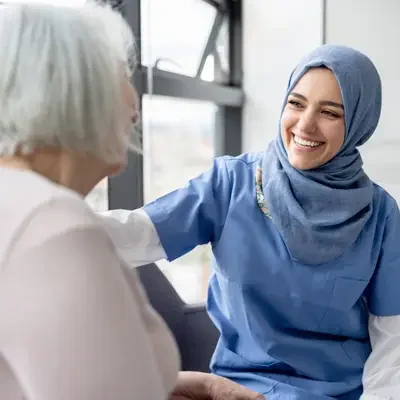 Muslim nurse talking to a senior patient at the hospital and smiling.